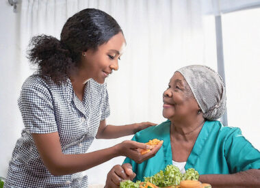 Woman helping an elder enjoy new foods